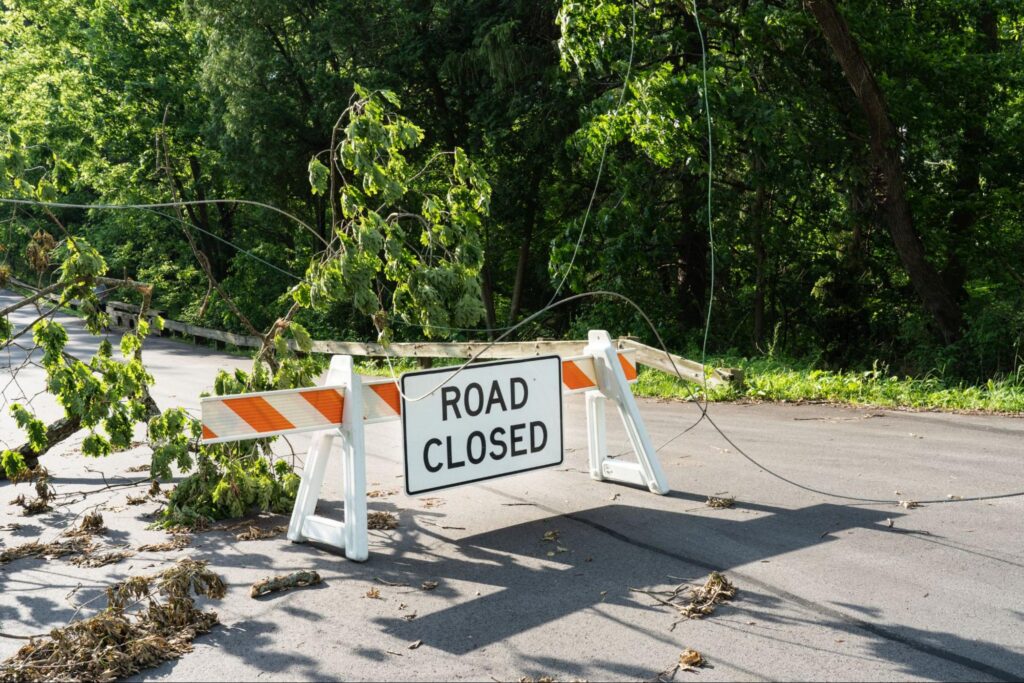 Road Closed sign with tree and power lines down after a big storm.